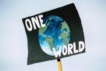 Sign showing planet and words "One World' (Unsplash/Markus Spiske)