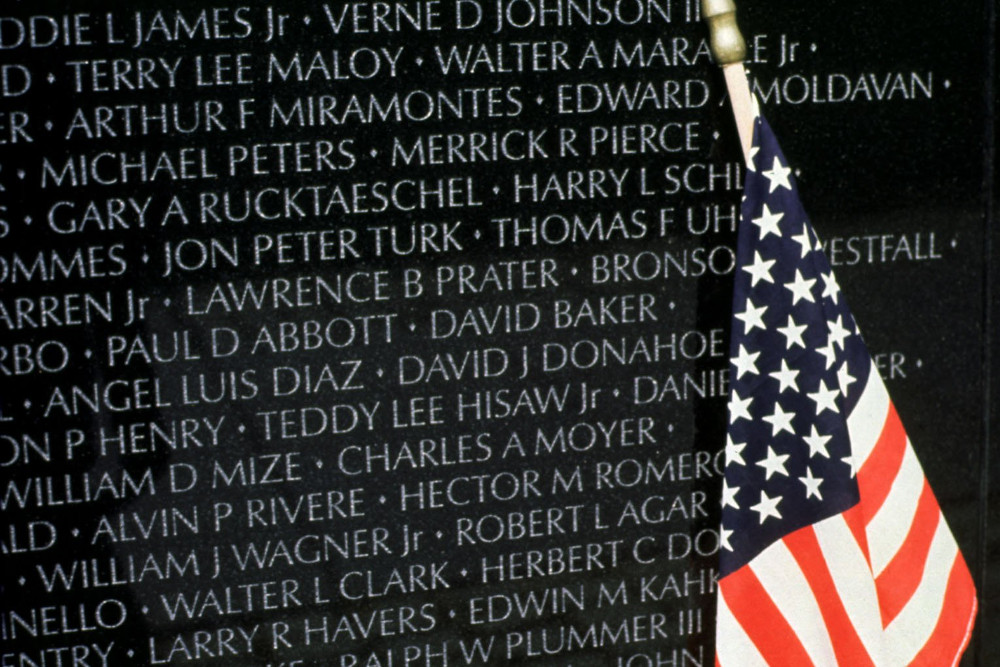A U.S. flag leans against the names of U.S. soldiers who died in Vietnam at the Vietnam War memorial in Washington. (CNS/Cleo)
