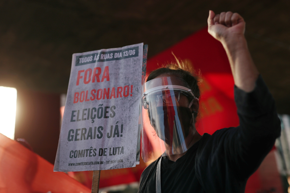 A demonstrator wearing a protective face shield and mask holds a banner during a protest against Brazilian President Jair Bolsonaro July 26, 2020, in Sao Paulo (CNS/Reuters/Amanda Perobelli) 
