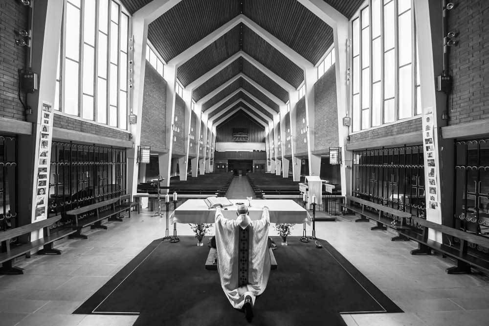 A priest kneels in front of the altar of an empty Holy Apostles Catholic Church in London Nov. 18, 2020. (CNS/Courtesy of Conference of Catholic Bishops of England & Wales/Marcin Mazur)