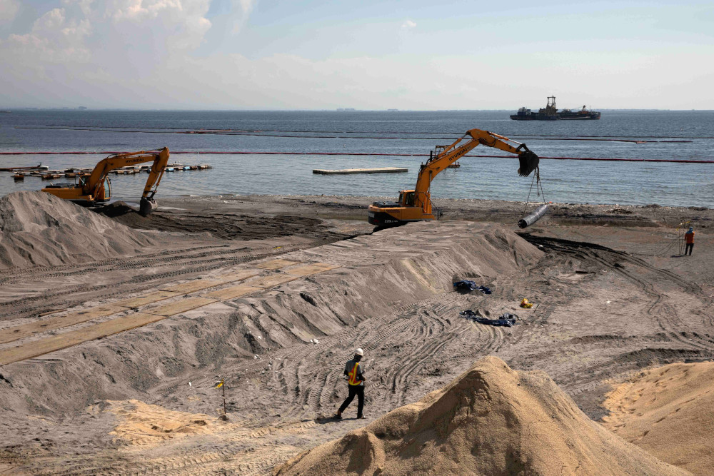 A worker stands on artificial sand or crushed dolomite, dumped on a portion of Manila Bay Sept. 4, 2020, as part of the Philippine government's efforts to rehabilitate and beautify the coastline. (CNS/Reuters/Eloisa Lopez)