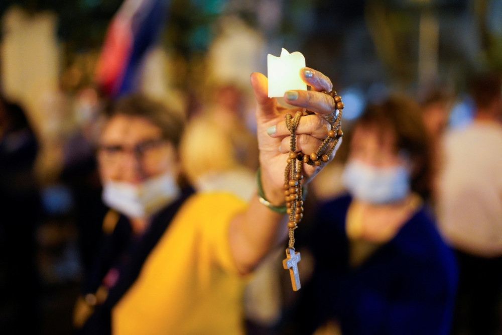 A woman holds a votive candle and a rosary during an anti-war protest outside the Russian Embassy in Montevideo, Uruguay, March 2 in support of Ukraine amid Russia's invasion. (CNS/Reuters/Ana Ferreira)